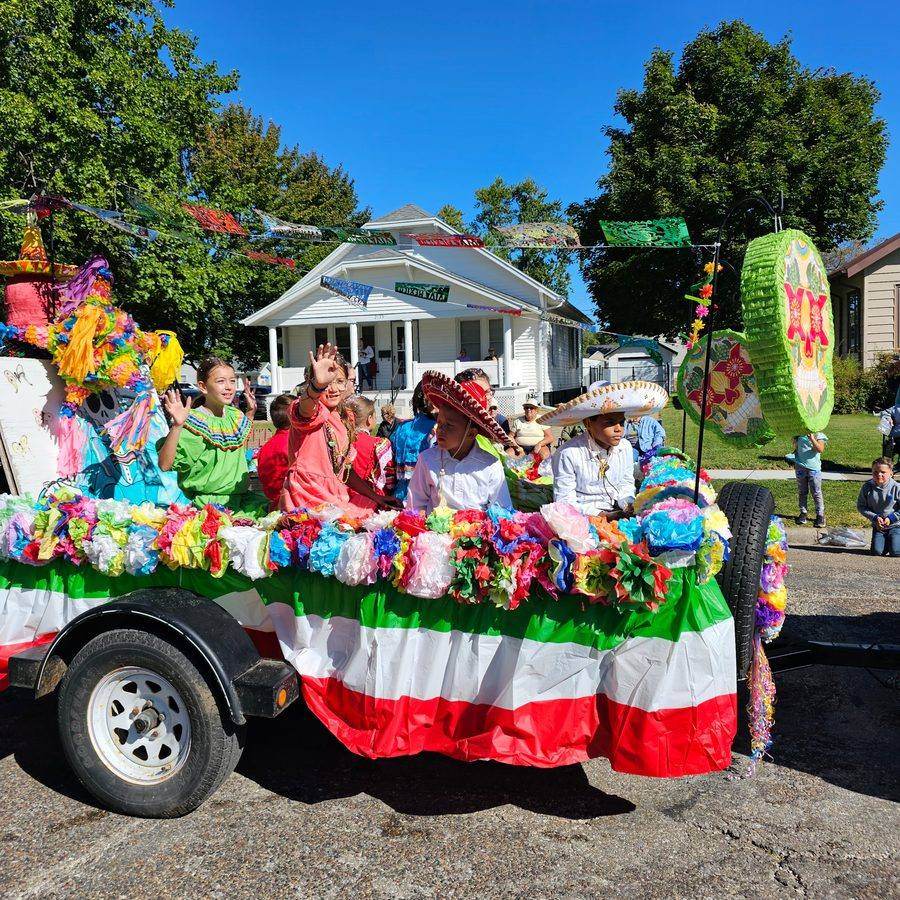 Children waving from a piñata-decorated parade float